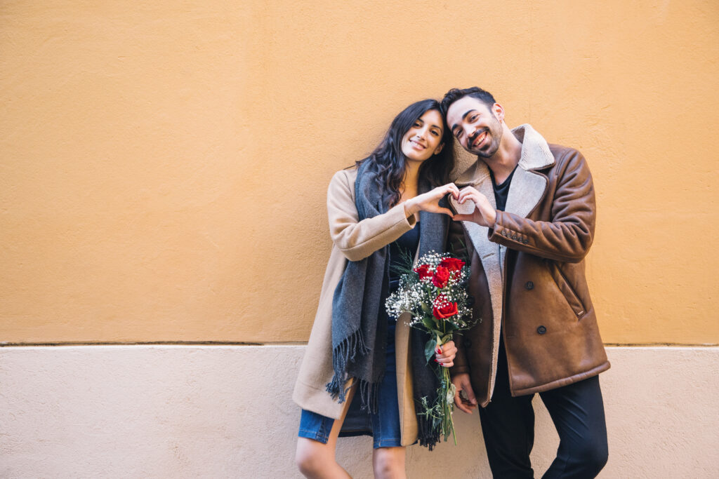 cute-couple-with-bouquet-showing-heart-gesture